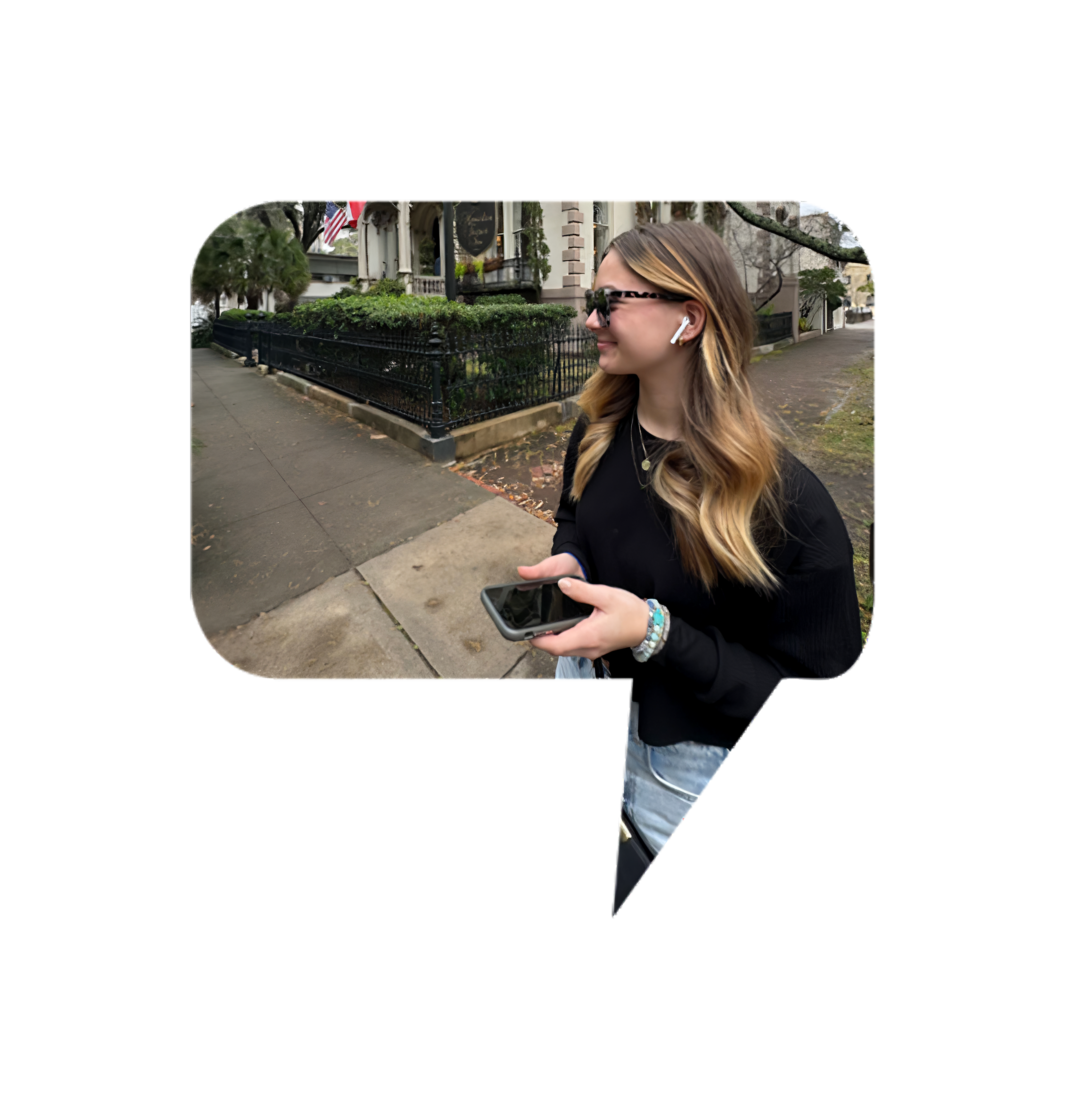 Young woman enjoying an audio tour while walking through a historic district, wearing wireless earbuds and holding a smartphone